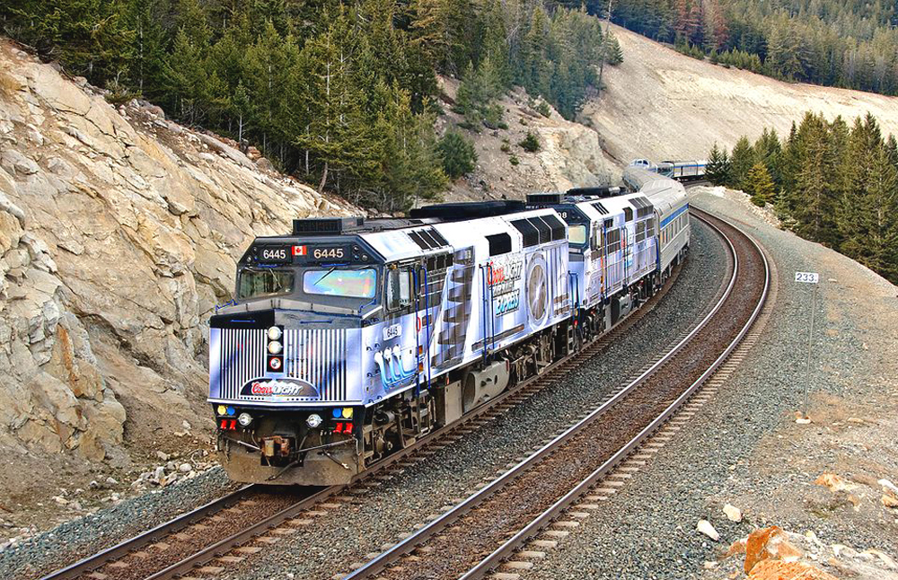 Passenger train with diesel locomotives dressed in black and silver graphics.