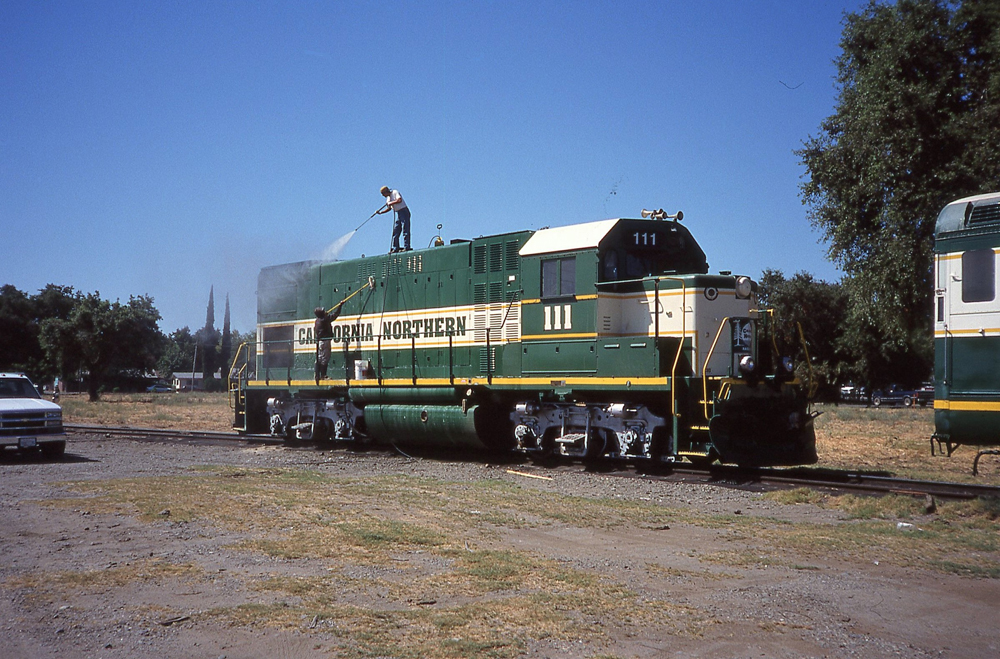green and white locomotive getting washed