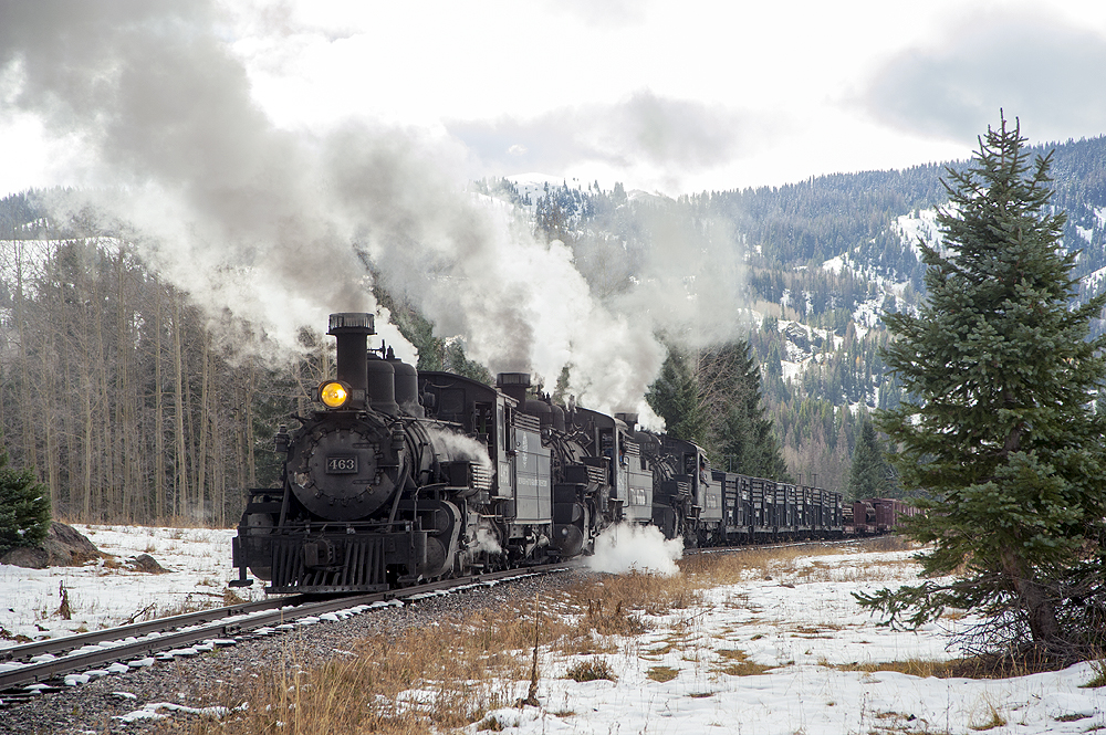 A steam locomotive hauled train passes through a snowy landscape.