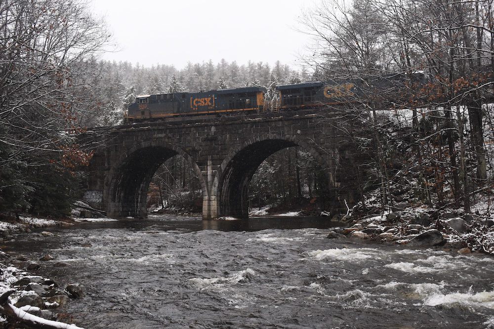 Winter scene of CSX fright train crossing a stone arch bridge