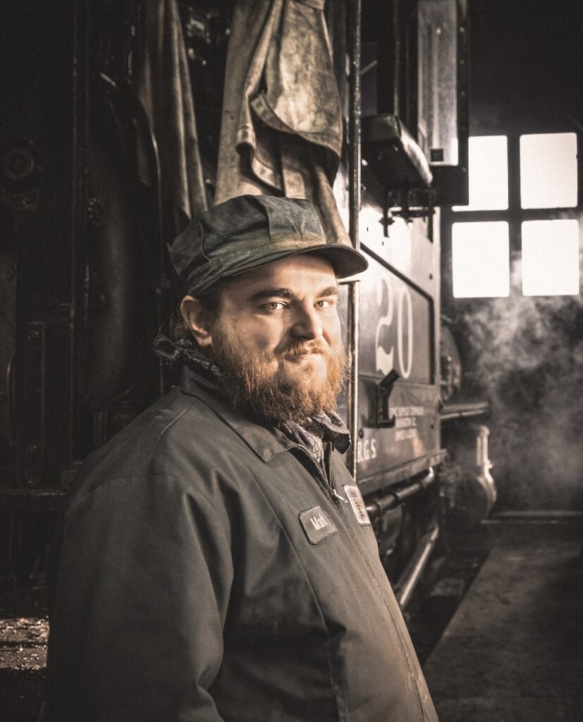 Portrait shot of crewman in front of a steam locomotive.
