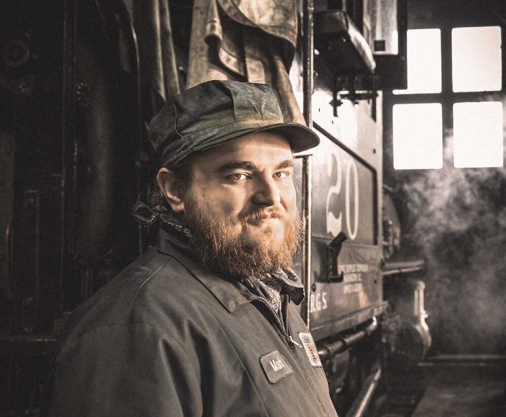 Portrait shot of crewman in front of a steam locomotive. 