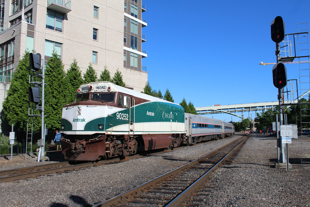 Green, white, and brown cab car with passenger coaches