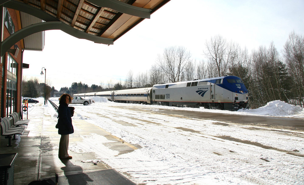 Train approaches station in snow-covered landscape