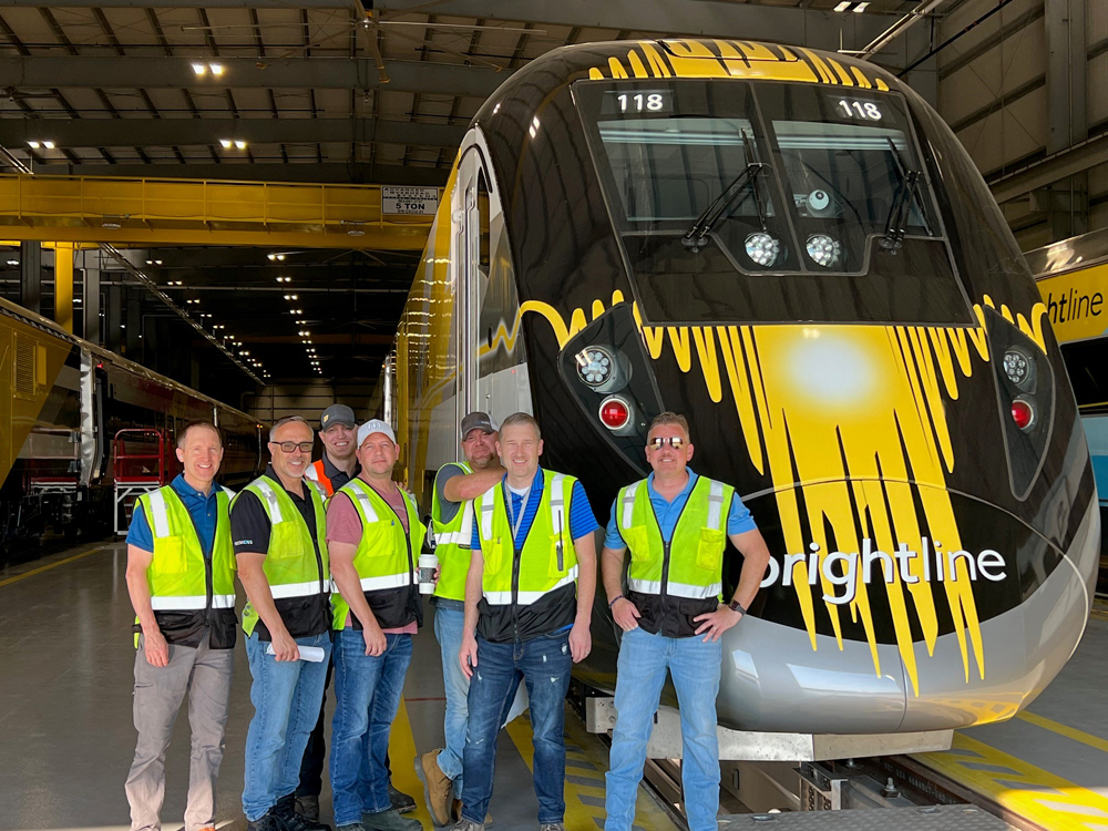 Group of people in hi-viz vests standing in front of train