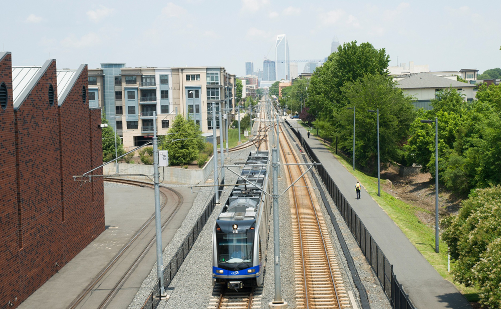 Overhead view of light rail train with city skyline in distance