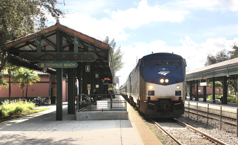 Passenger train arrives at station with covered platform