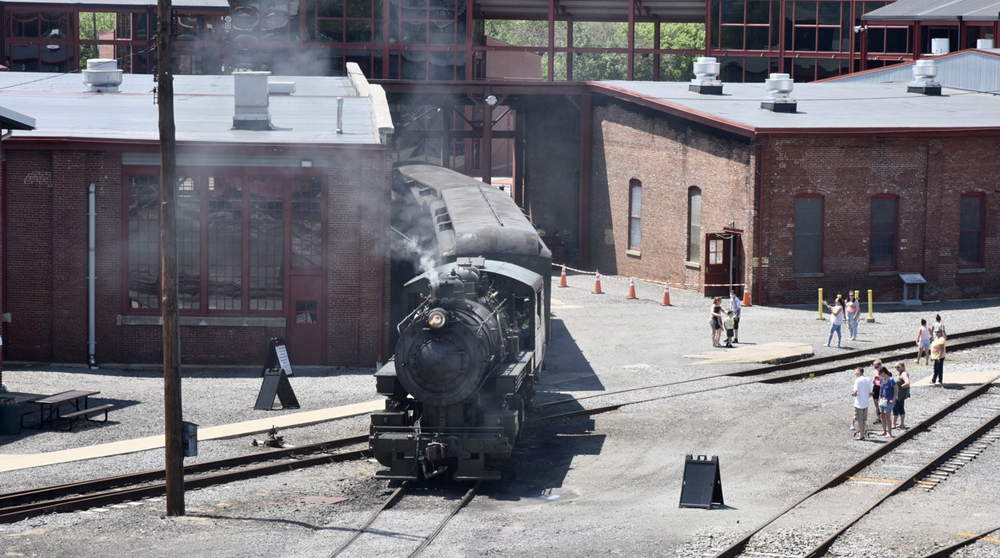 Steam locomotive moving between buildings