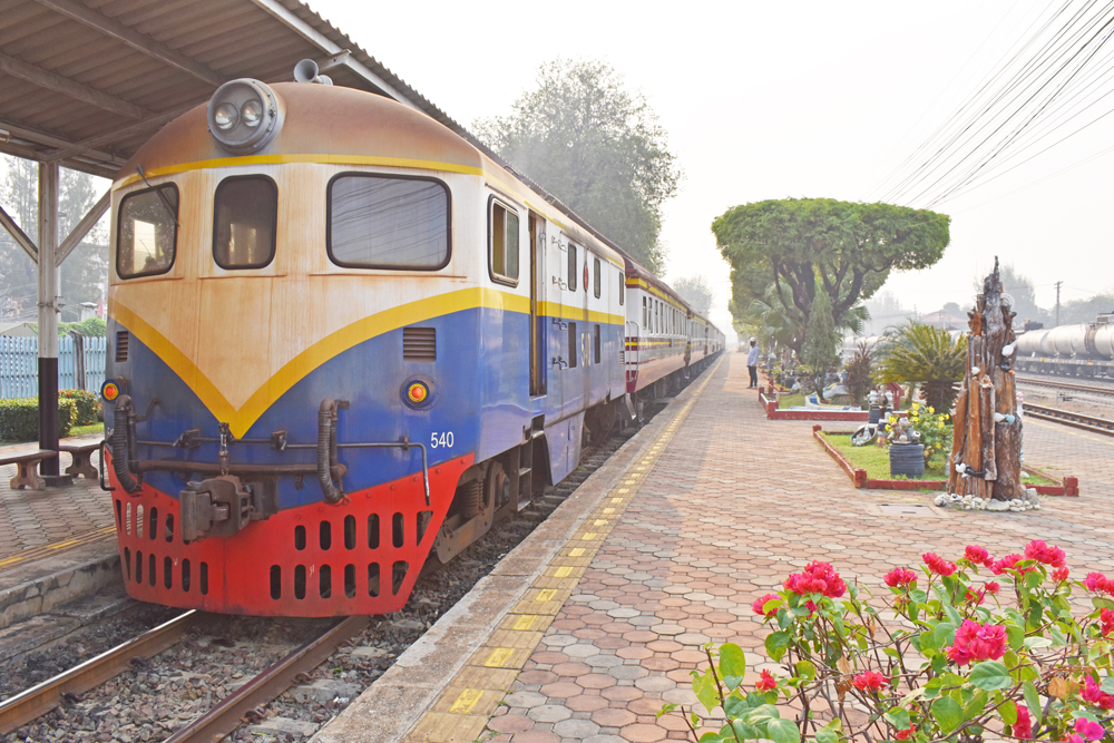 Blue and tan shovel-nose diesel locomotive with red pilot at station