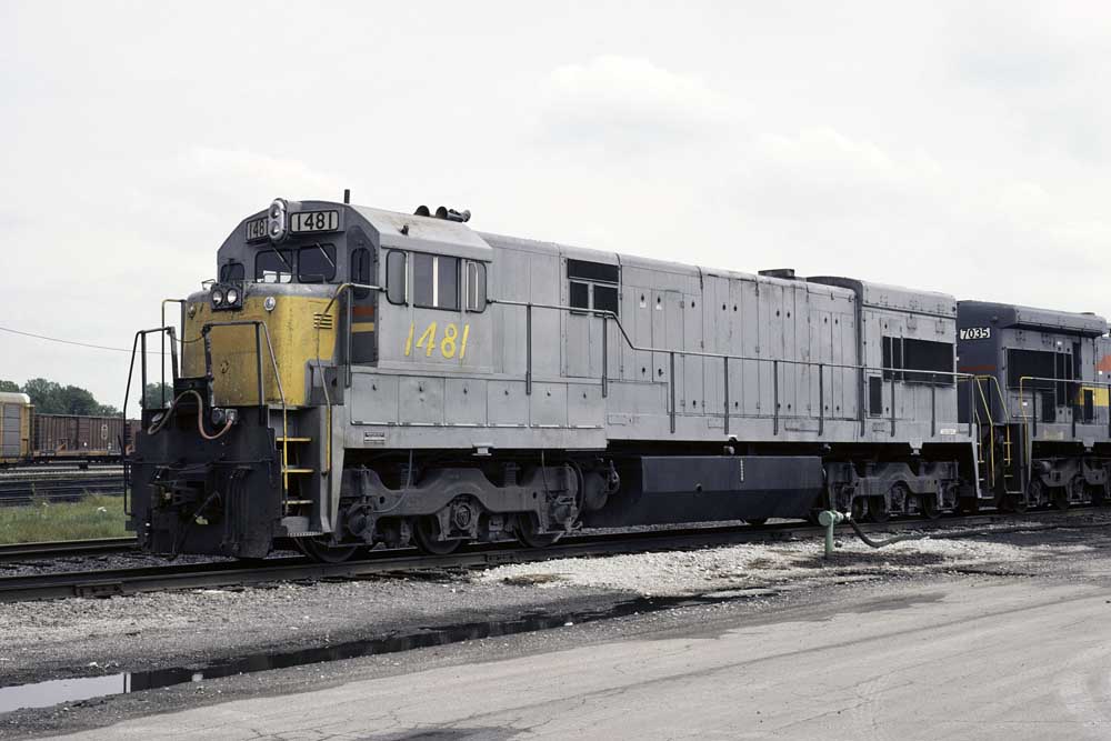 Gray-and-yellow diesel locomotive in rail yard