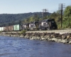 Three black-and-white diesel Penn Central locomotives on freight train along river