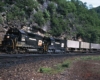 Penn Central locomotives on a freight train, one has an orange-and-white logo