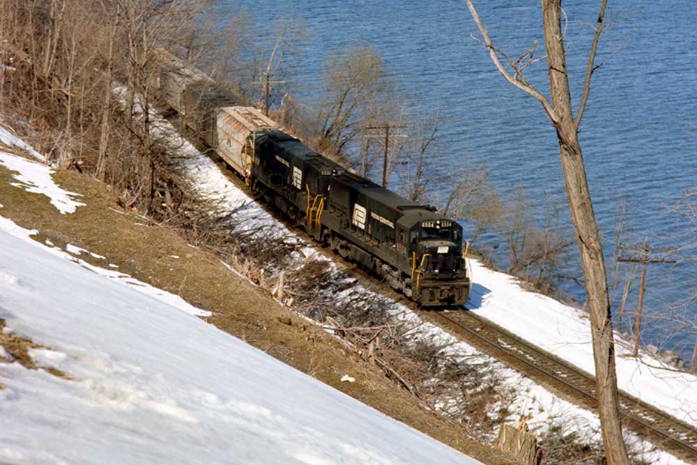 Two Penn Central locomotives with freight train on shoreline