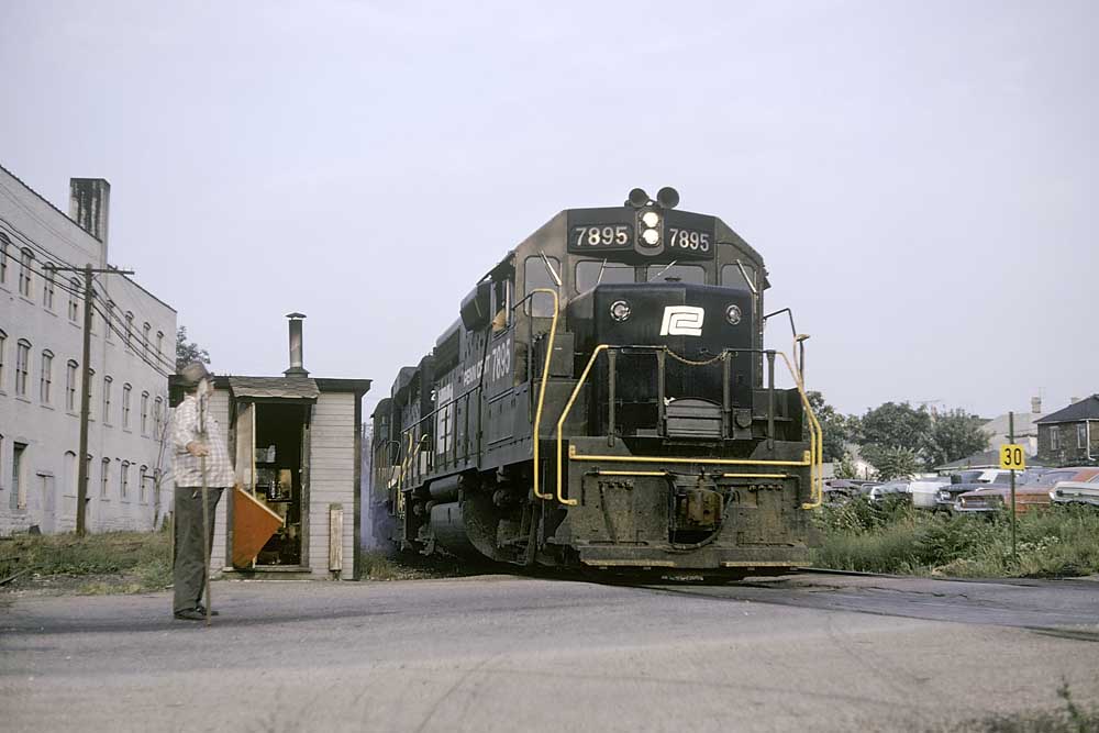 Nose of black-and-white diesel Penn Central locomotives crossing into street