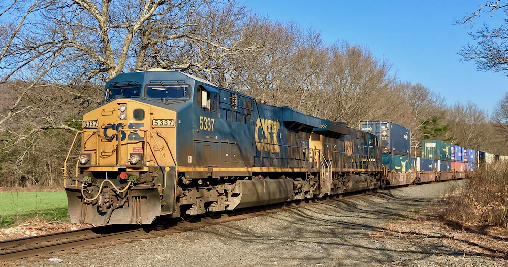 Blue and yellow locomotives pulling a double-stack train