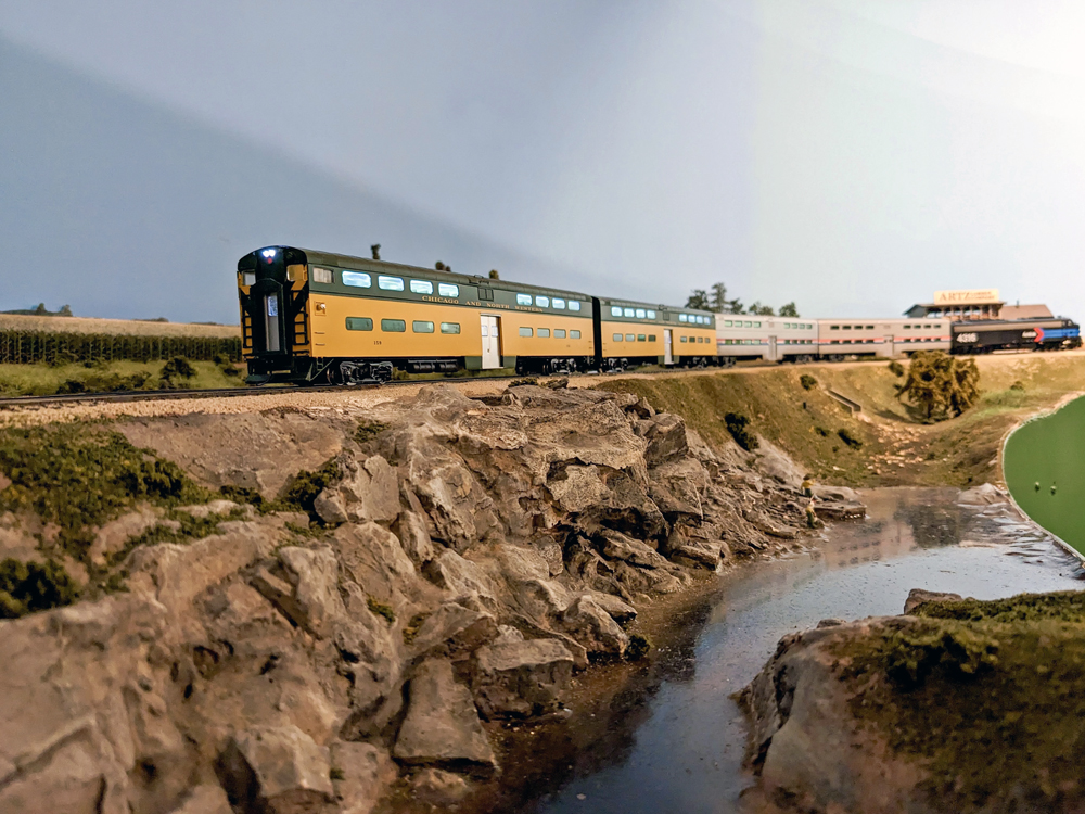 A model passenger train travels past a river