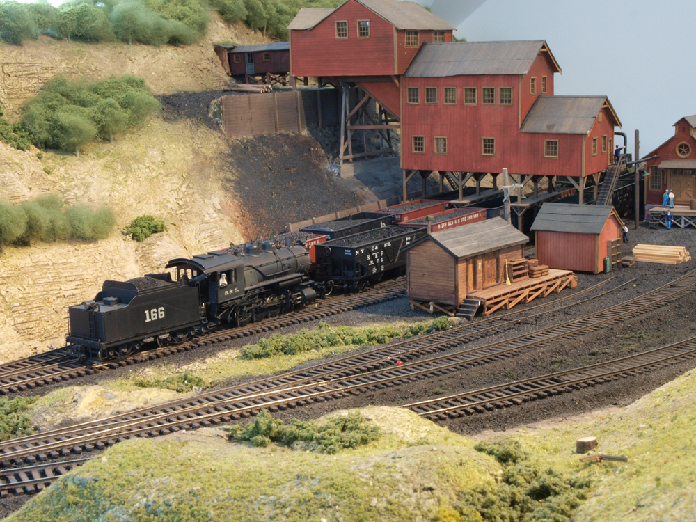 A model steam engine switches cars at a coal mine.