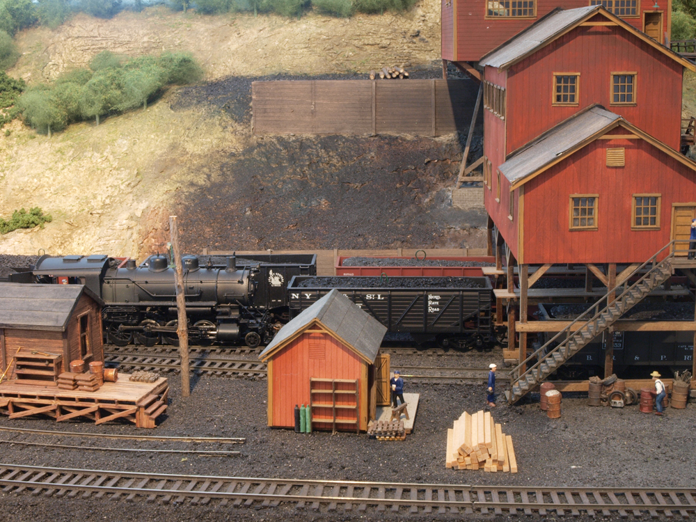 A model steam engine and coal hoppers sit under a coal mine.