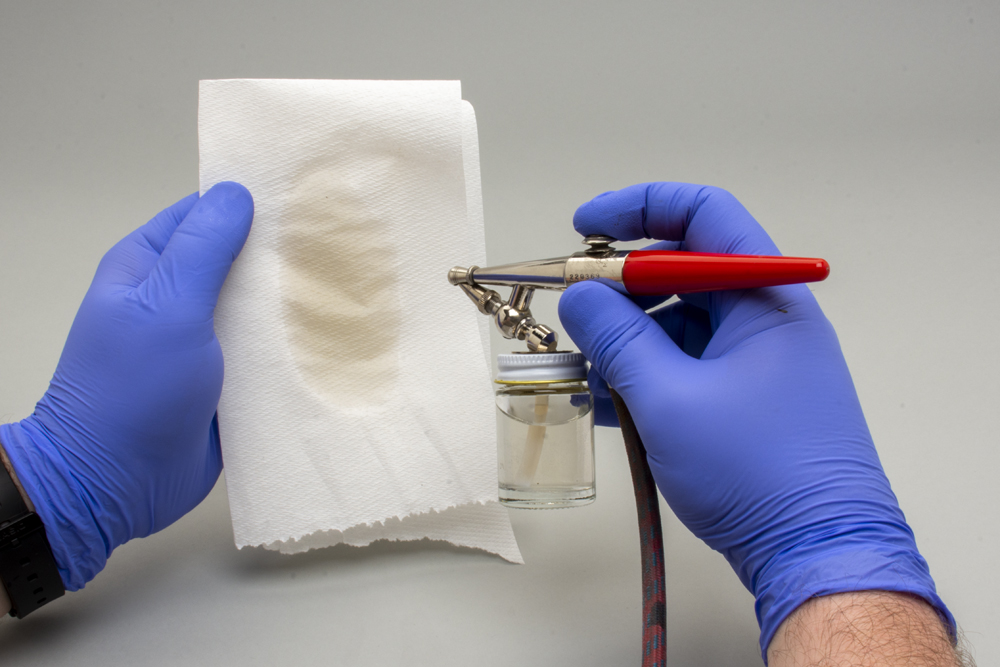 Color photo showing water being sprayed on paper towel.