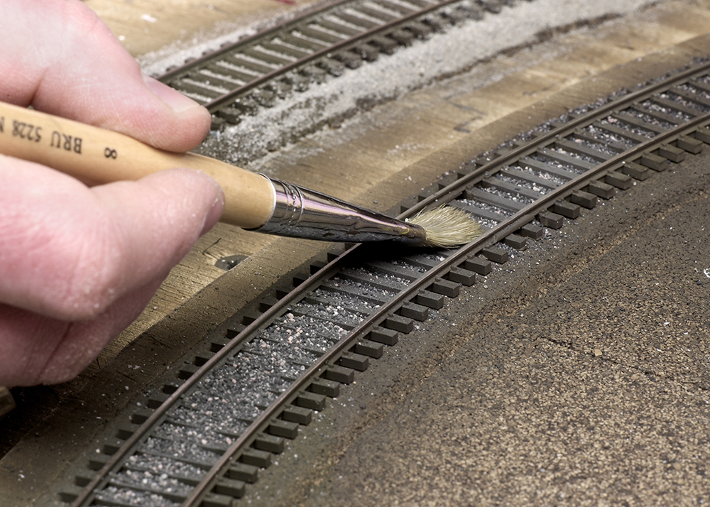 Color photo showing ballast being spread with a paintbrush.