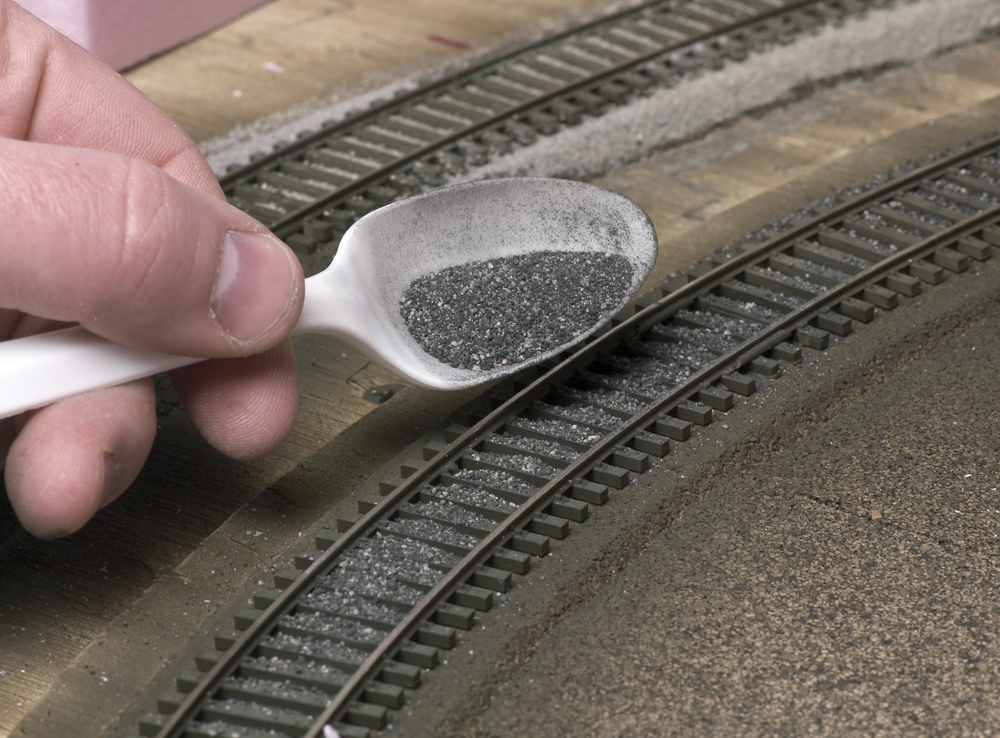 Color photo showing ballast being applied to HO scale track.