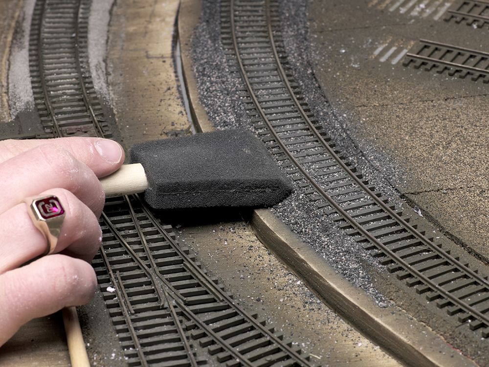 Color photo of ballast being shaped with foam paintbrush.