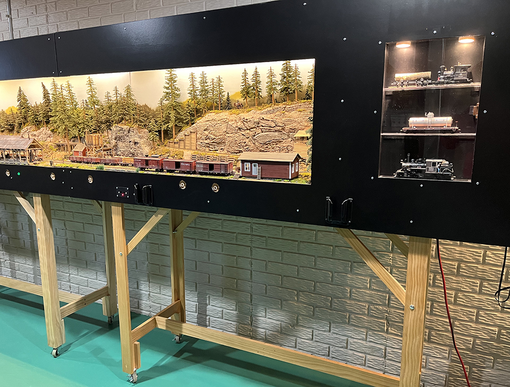 A modeled mountain railroad scene inside a lighted display box with black boarders