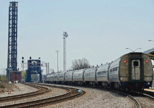 Passenger train with two draw bridges in background. One bridge is raised. High iron baseball — AAA minor league stadiums.