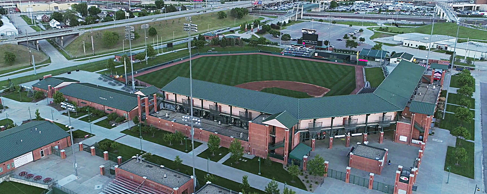 Aerial view of baseball stadium with train line outside right field. This is high iron baseball — exploring independent leagues.