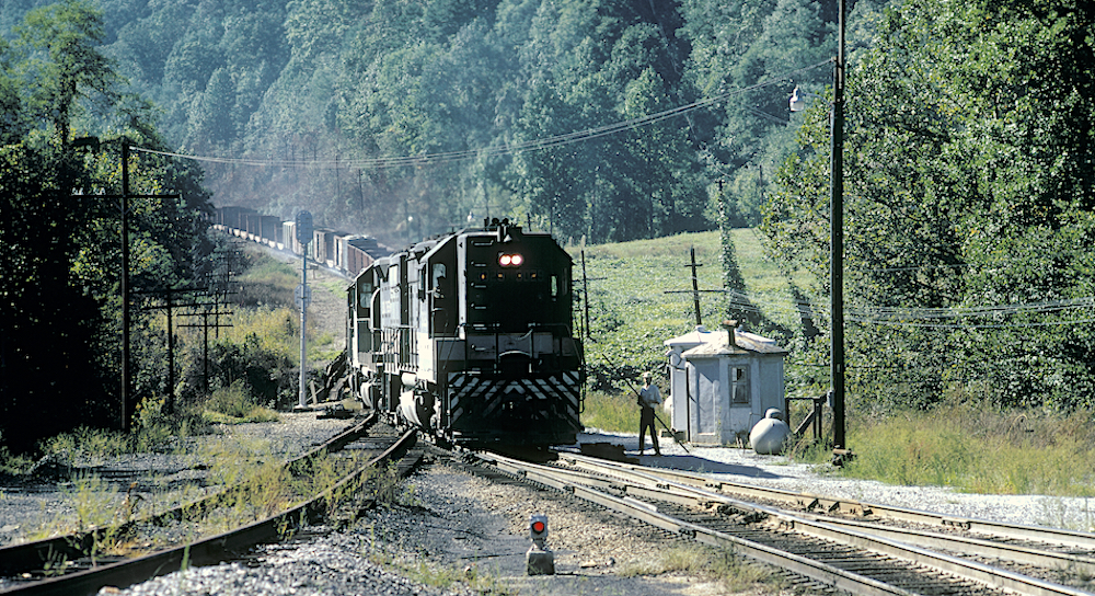 Locomotives at bottom of steep grade with train on hill behind
