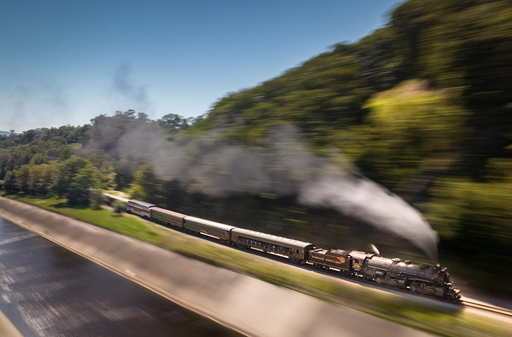 Steam locomotive with motion blur and mountain scenery.