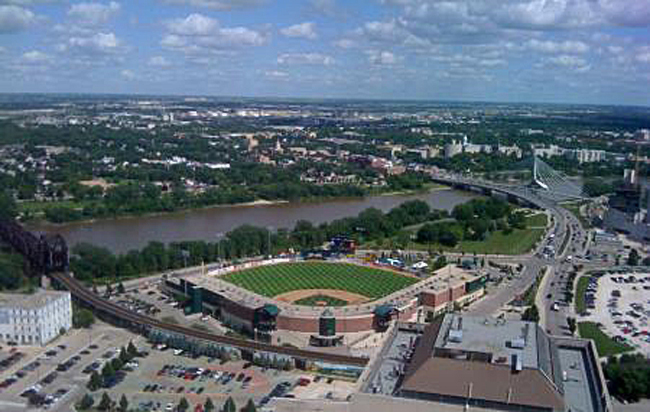 Baseball stadium by river with train bridge in foreground. This is high iron baseball — exploring independent leagues.