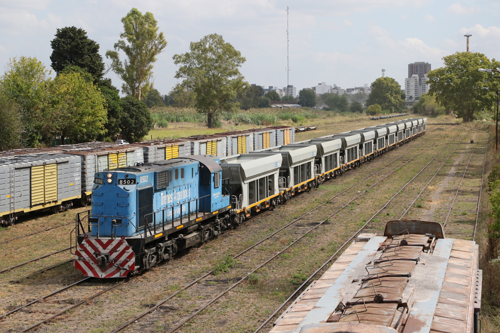 Blue Alco locomotive with short string of hopper cars