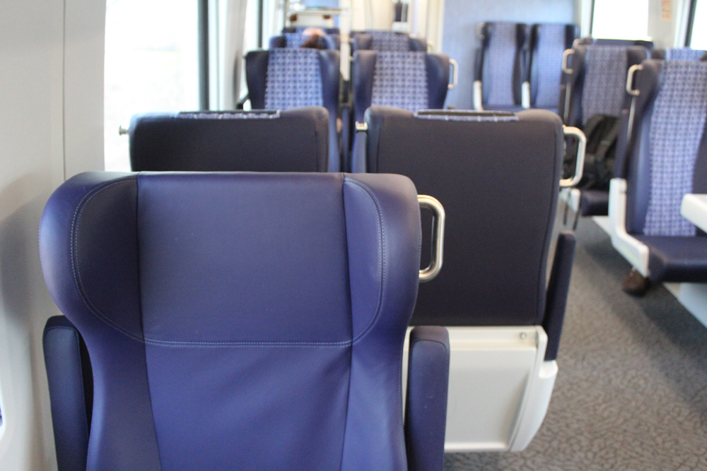 View of part of business-class seat and narrower coach seat