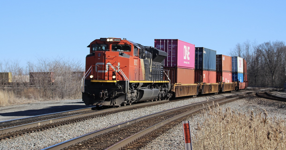 Intermodal train with one red and black locomotive on curve