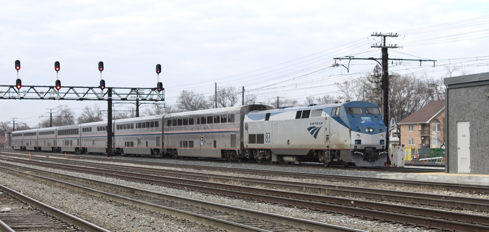 Passenger train passes under signal bridge