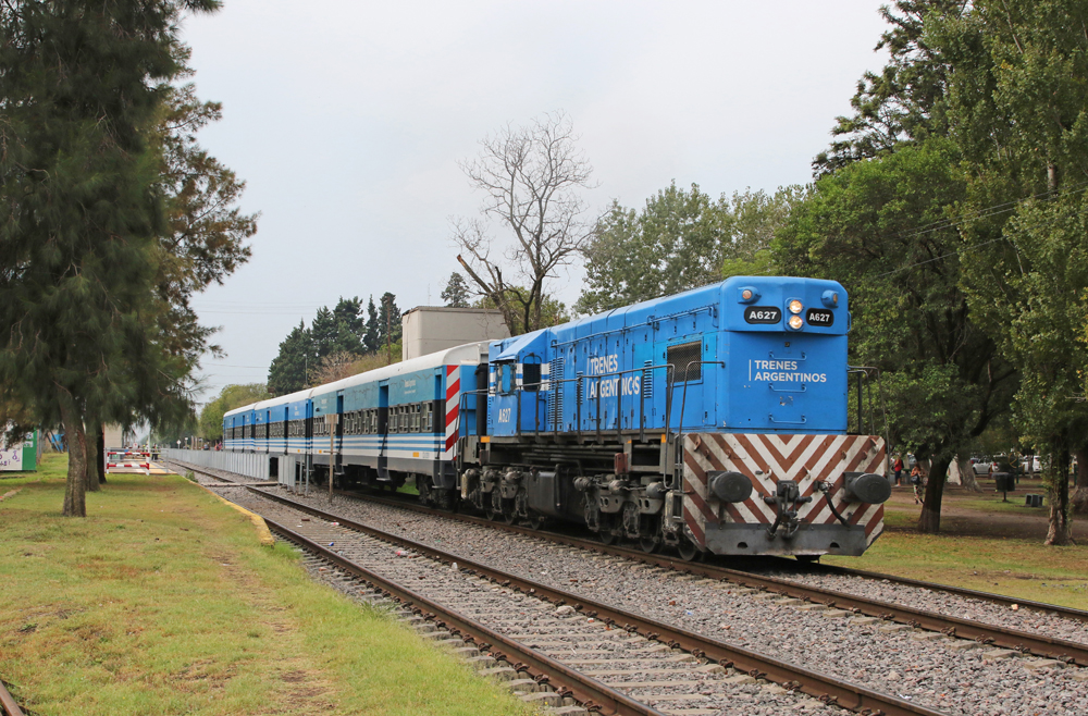 Blue diesel leading commuter train along double-track line