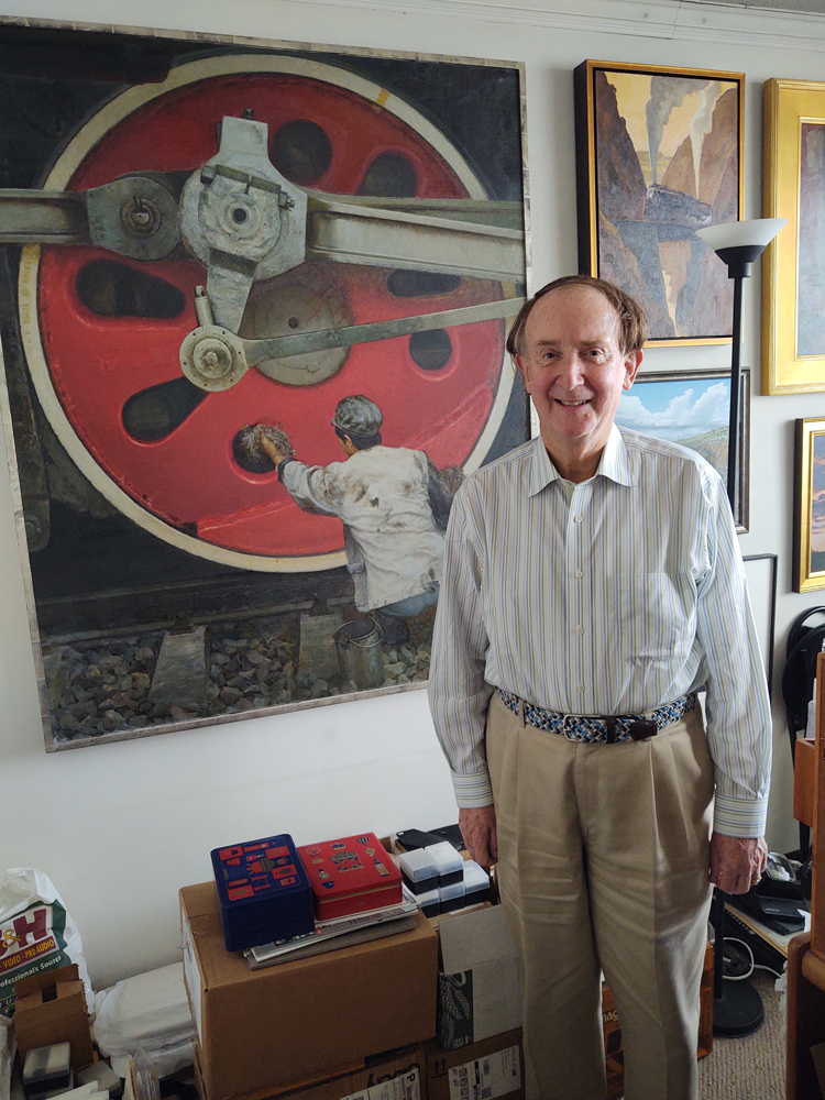 Man standing in front of painting of worker with red locomotive driving wheel