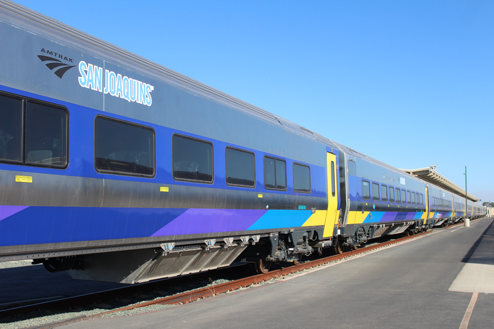 String of passenger cars with brightly colored striping sitting in storage