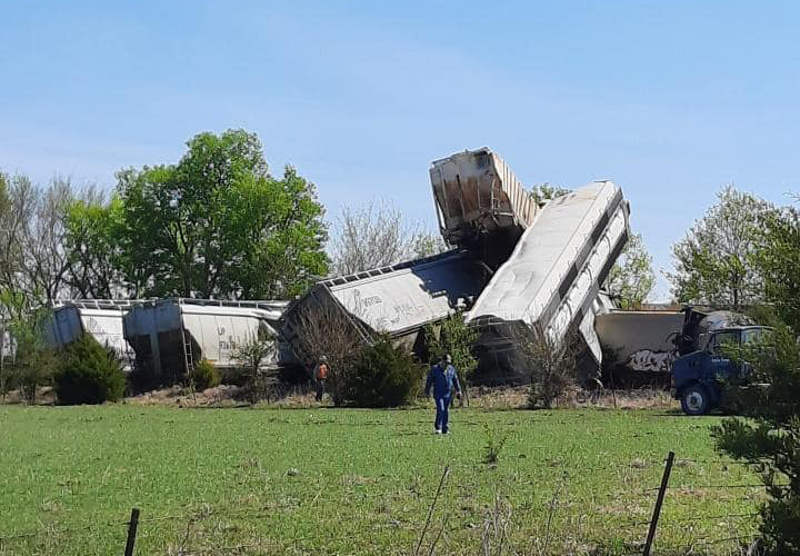 Derailed hopper cars, including several stacked above the right-of-way