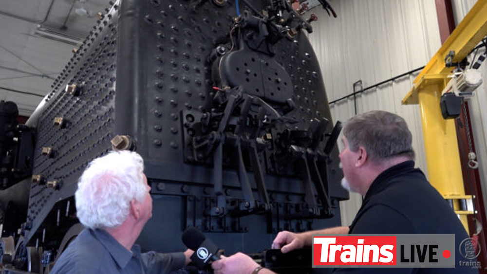 Two men looking at a steam locomotive firebox under restoration.