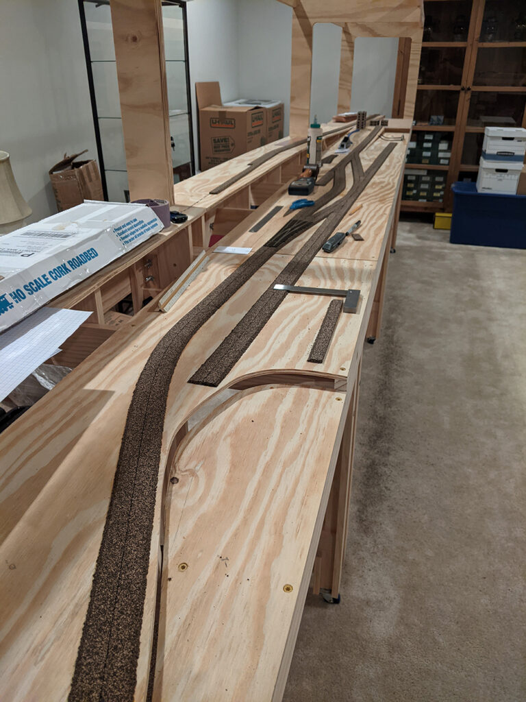 Brown strips set out in straight and curved lines on a plywood surface