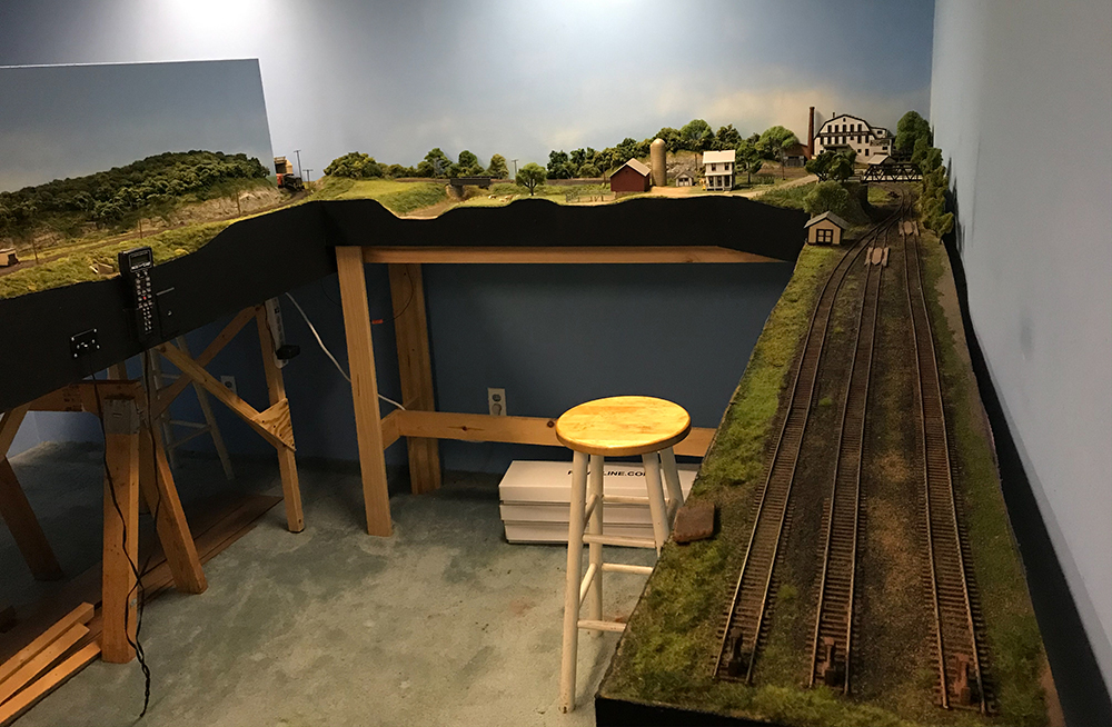 Model train set built into a small room featuring trains running around three walls of the room