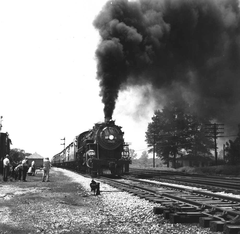 Steam locomotive passing by groups of people taking photos