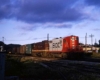 Red-and-white and maroon-and-gold Soo Line diesel locomotives on passenger train at sunset