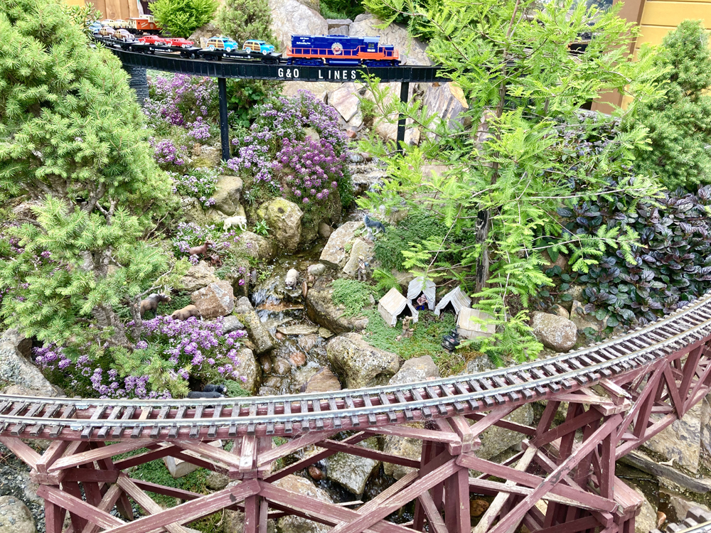 model train on bridge with trestle in front on garden railway