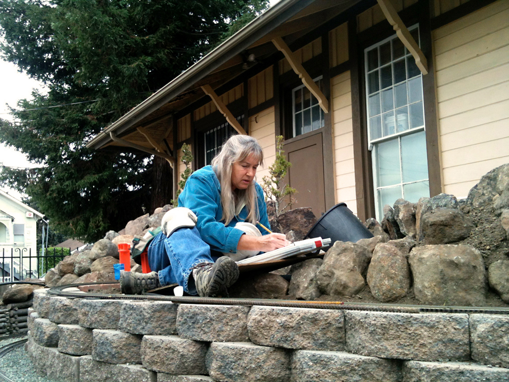 woman sitting on stone pavers next to house