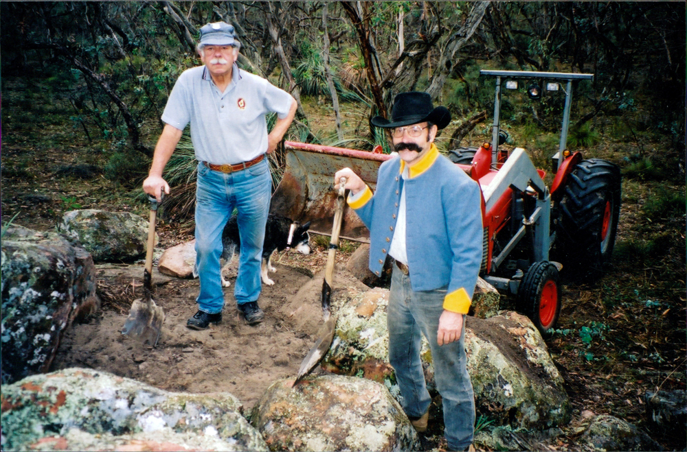 Two men with shovels, next to rocks and dirt