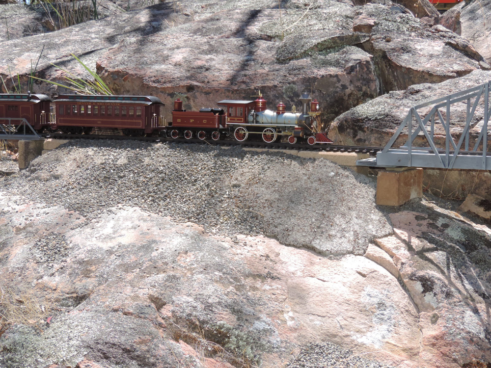 model steam locomotive on track next to large rocks