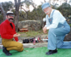 two men kneeling down near garden railway